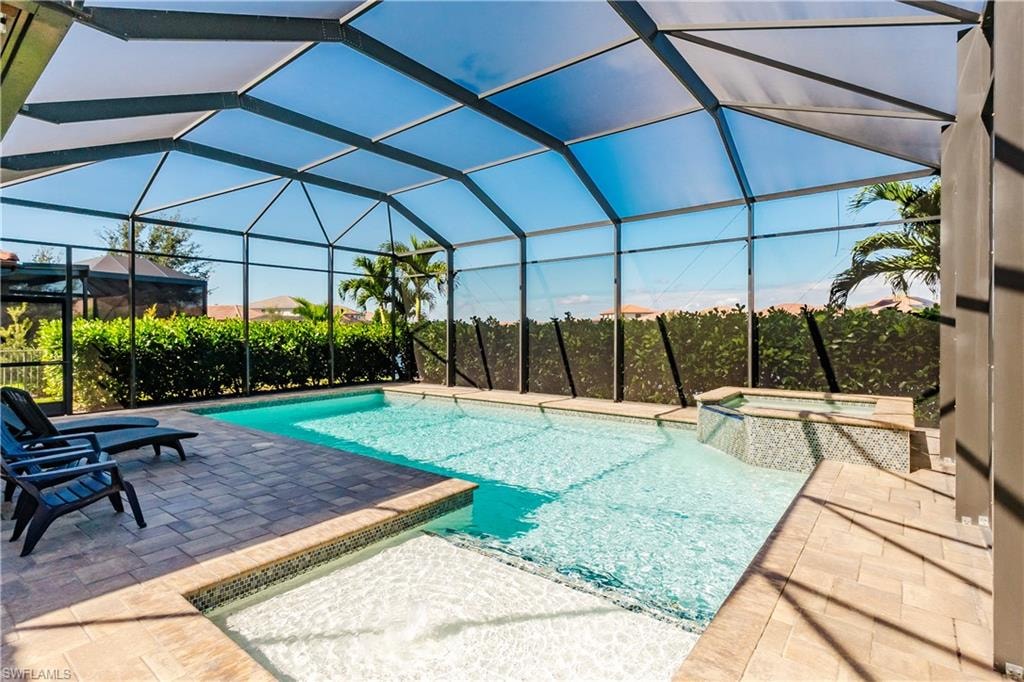 View of swimming pool with a sunroom, a patio area, and glass enclosure