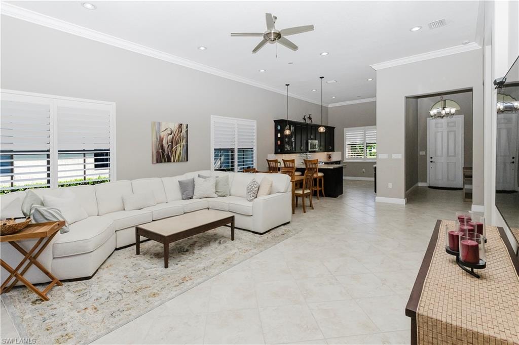 Living area featuring ornamental molding, recessed lighting, ceiling fan, a chandelier, and light tile patterned flooring