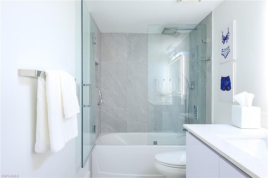 Full bath featuring vanity and bath / shower combo with glass door