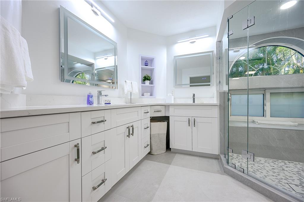 Bathroom with double vanity, a stall shower, and light tile patterned floors