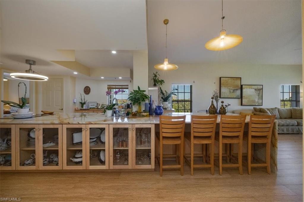 Kitchen with hanging light fixtures, open floor plan, light stone countertops, light wood-style floors, and recessed lighting