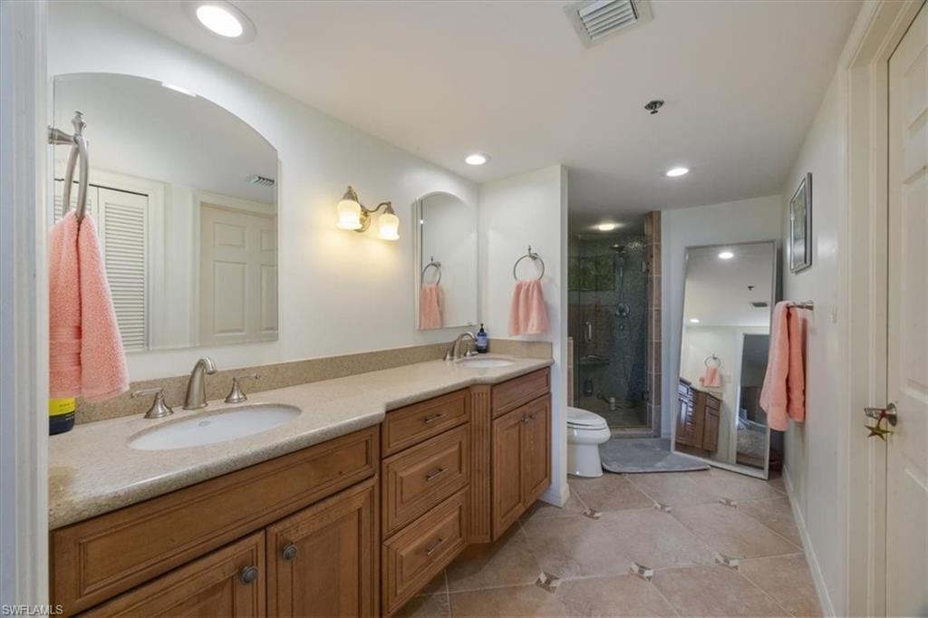 Bathroom with a stall shower, double vanity, light tile patterned floors, and recessed lighting