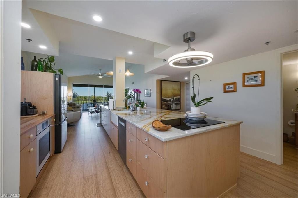 Kitchen featuring light wood-style floors, open floor plan, an island with sink, ceiling fan, and recessed lighting