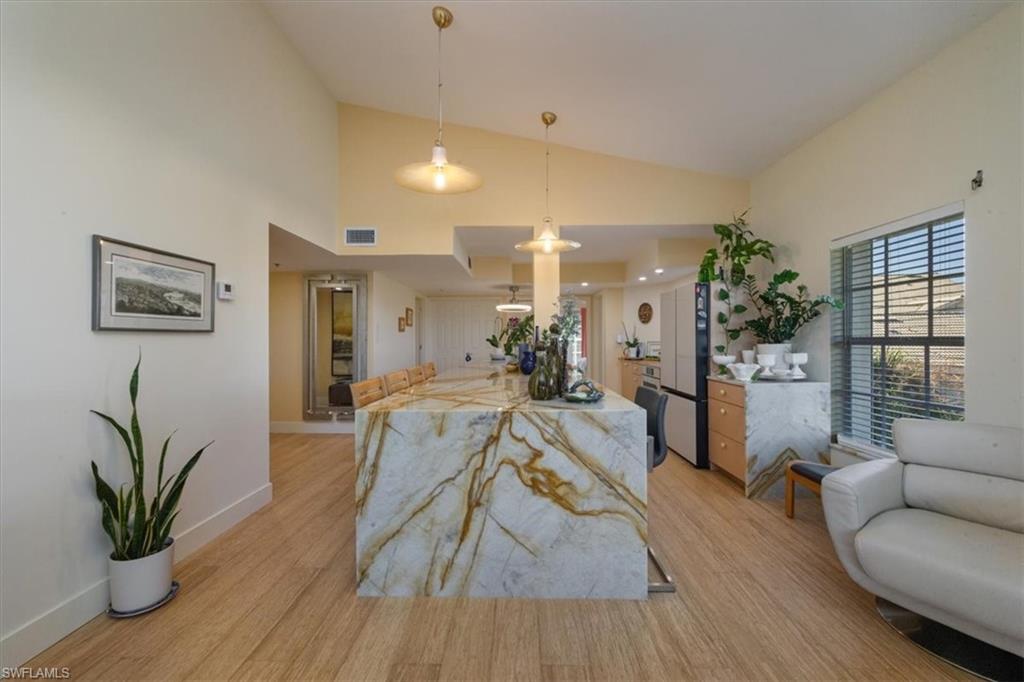 Kitchen with hanging light fixtures, open floor plan, light stone countertops, light wood-style floors, and recessed lighting