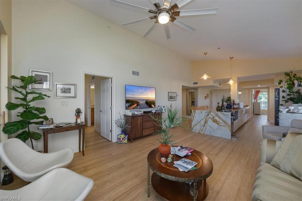 Living room featuring light wood-style flooring, high vaulted ceiling, and a ceiling fan