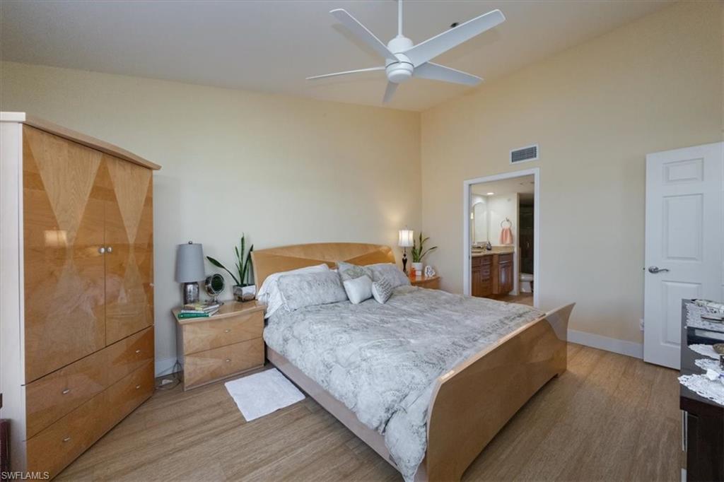 Bedroom featuring light wood-style floors, ensuite bathroom, and a ceiling fan