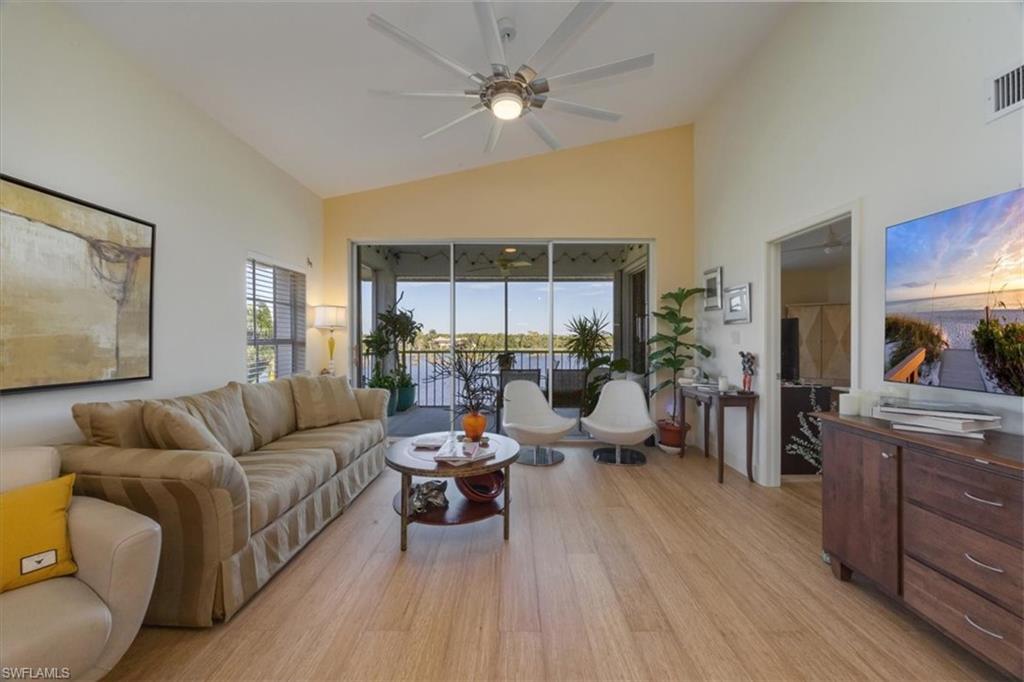 Living room with light wood finished floors, high vaulted ceiling, and ceiling fan