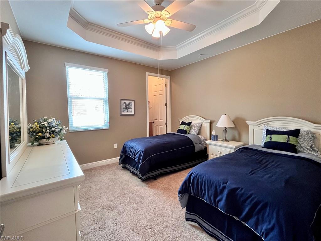 Bedroom #3 featuring twin beds, walk in closet, dresser, a raised ceiling, light carpet, and a ceiling fan
