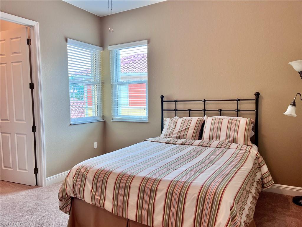Bedroom#2 featuring light carpet, queen bed, walk in closet, ceiling fan and TV