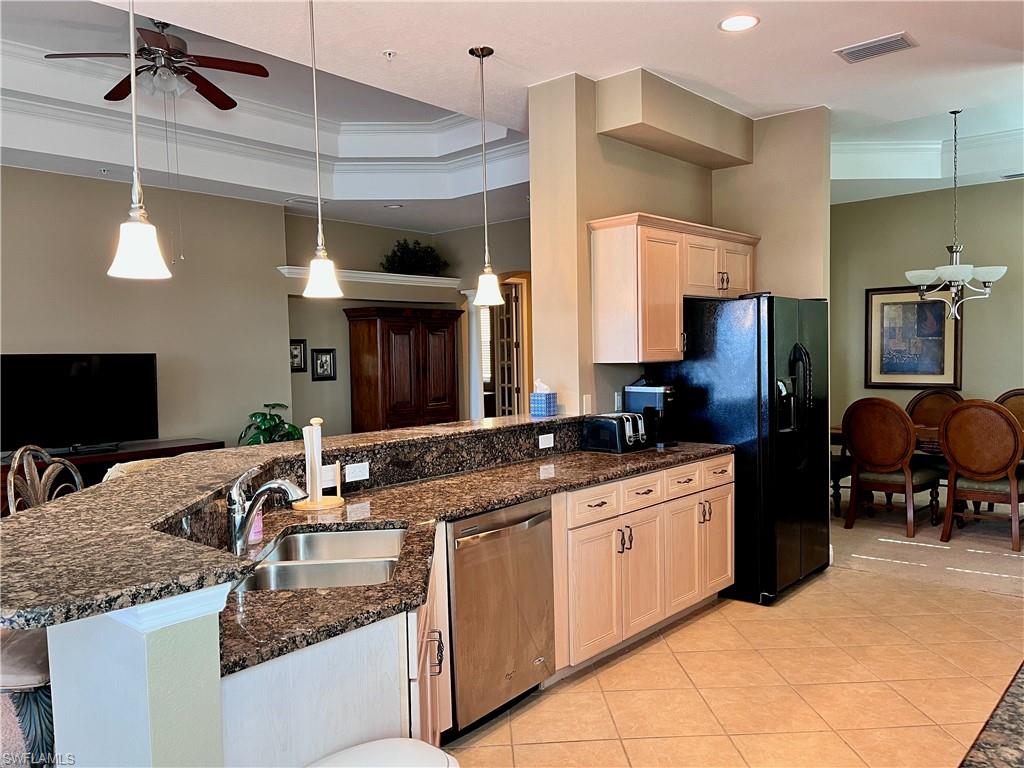 Kitchen featuring a peninsula, dark stone counters, hanging light fixtures, stainless steel dishwasher, and ornamental molding