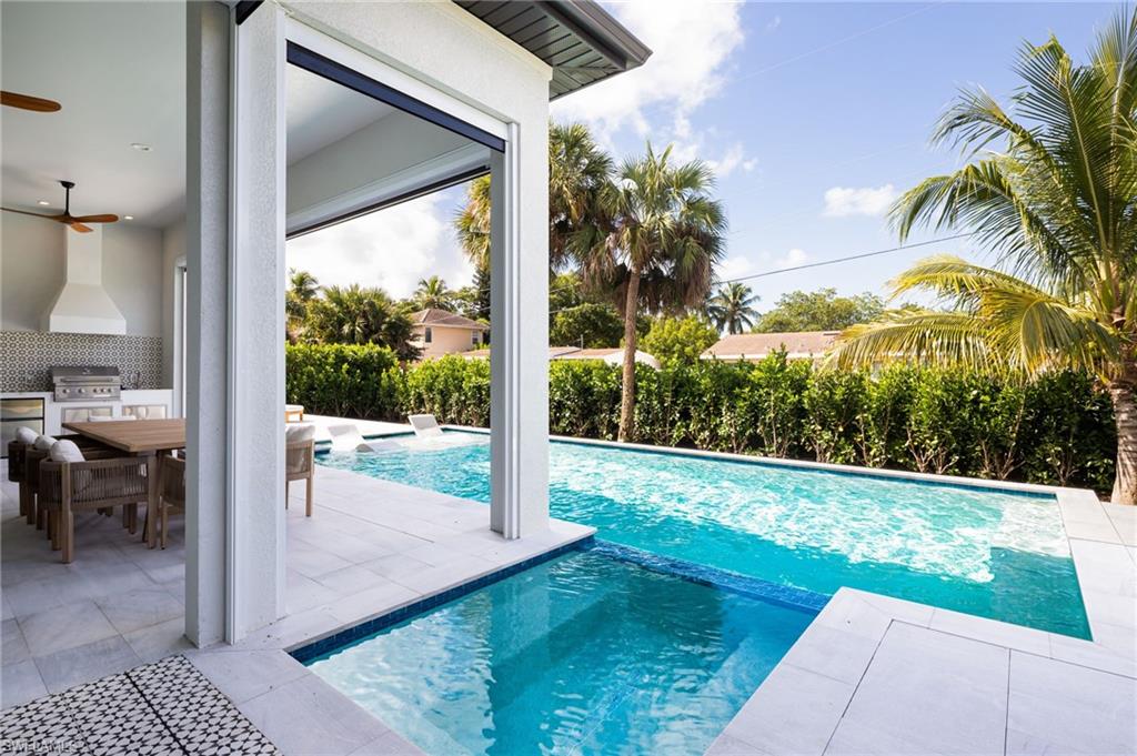 View of swimming pool with exterior kitchen, a patio, a pool with connected hot tub, a ceiling fan, and outdoor dining space