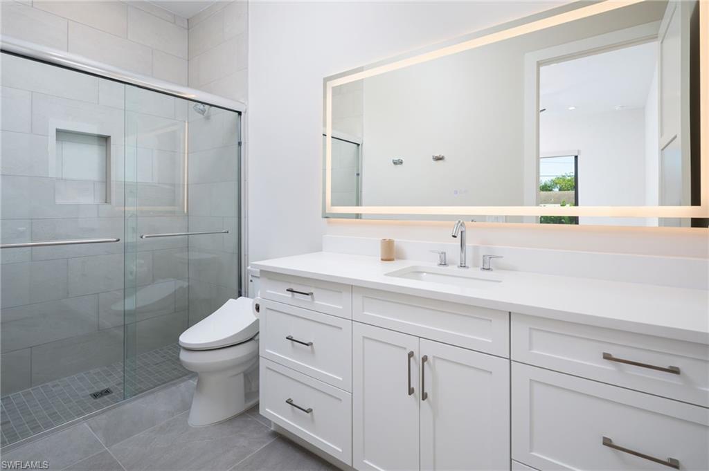 Bathroom featuring a shower stall, vanity, and light tile patterned flooring