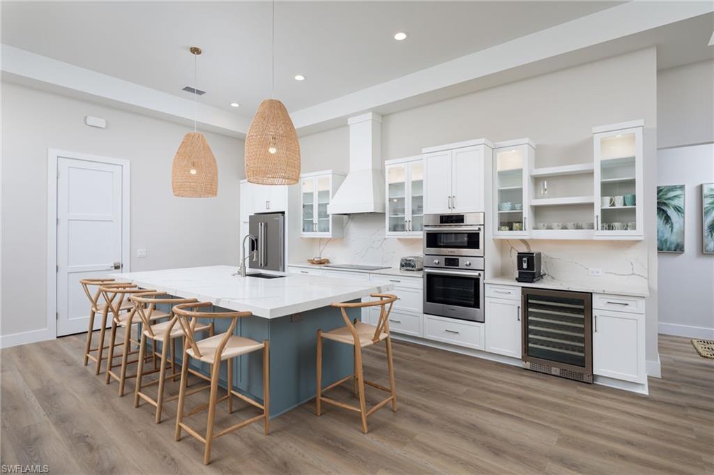 Kitchen with white cabinets, tasteful backsplash, glass insert cabinets, decorative light fixtures, and recessed lighting