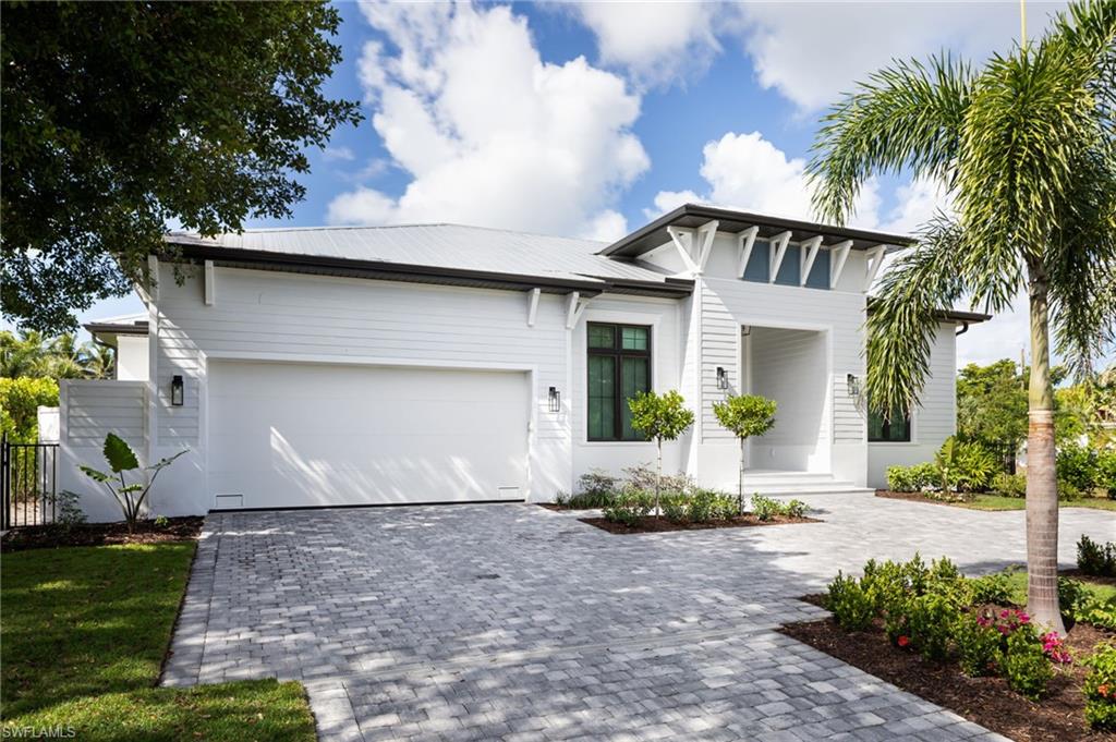 View of front facade featuring decorative driveway, an attached garage, and a metal roof