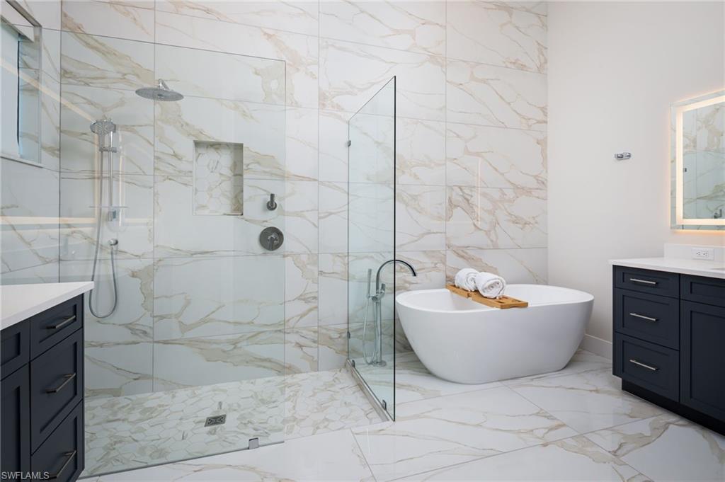 Full bathroom with vanity, a soaking tub, a marble finish shower, and light marble finish flooring