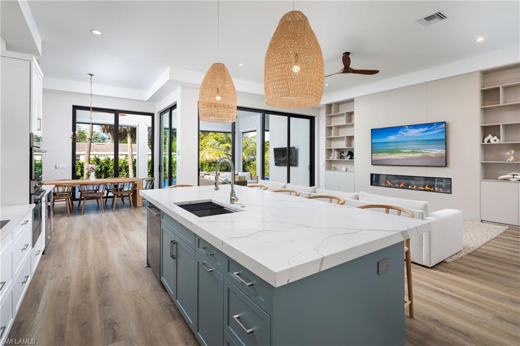 Kitchen with light stone countertops, white cabinetry, a kitchen bar, decorative light fixtures, and recessed lighting