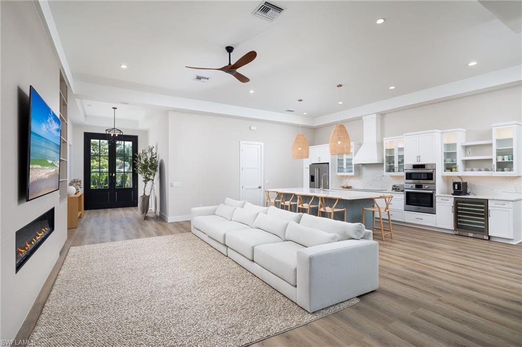 Living area featuring light wood finished floors, wine cooler, french doors, ceiling fan, and recessed lighting