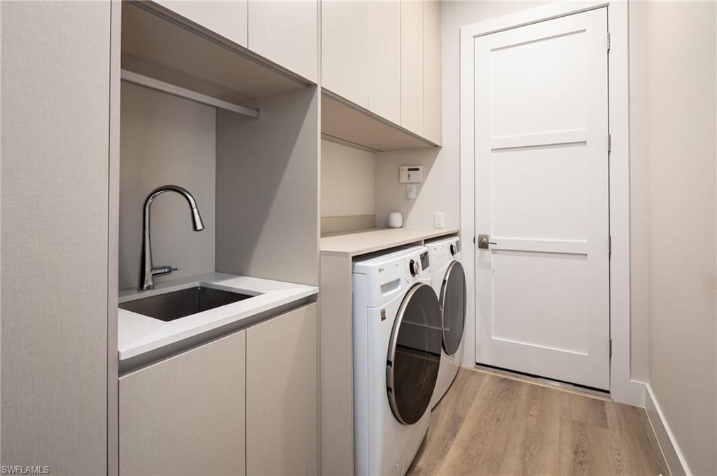 Laundry room featuring cabinet space, light wood-type flooring, and independent washer and dryer