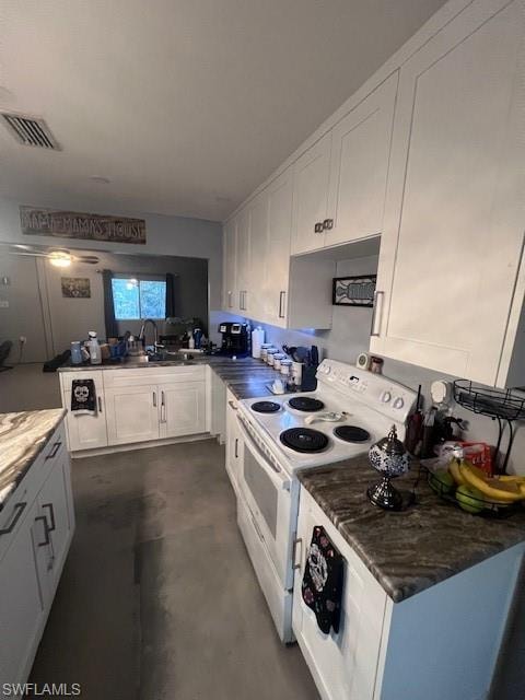 Kitchen featuring stove, white cabinetry, finished concrete flooring, dark countertops, and a peninsula