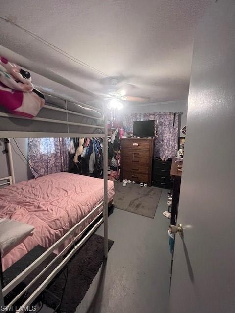 Bedroom with concrete floors, a textured ceiling, and a ceiling fan