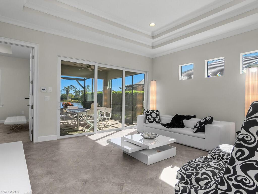 Living room leads to the lanai and pool area, a raised ceiling, recessed lighting, and ornamental molding.