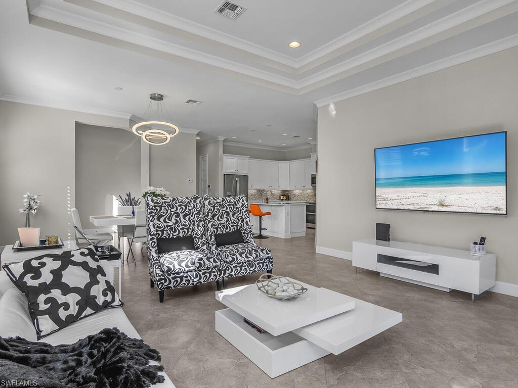 Living room featuring recessed lighting, ornamental molding, tile floors, and a tray ceiling.