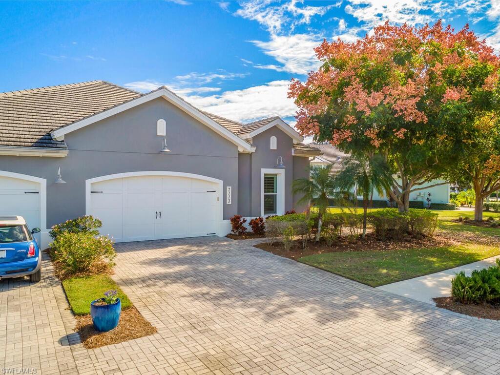 Coastal-style home with a tiled roof, decorative driveway, stucco siding, and an attached two car garage.