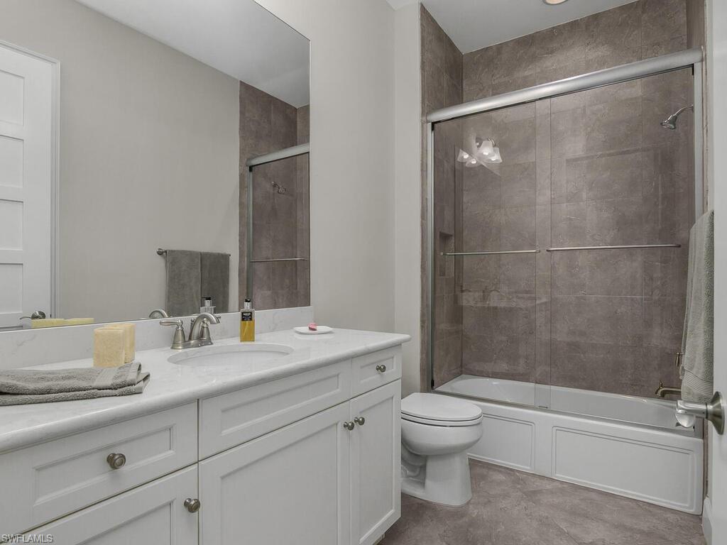 Guest bathroom featuring vanity and combined bath / shower with glass door.