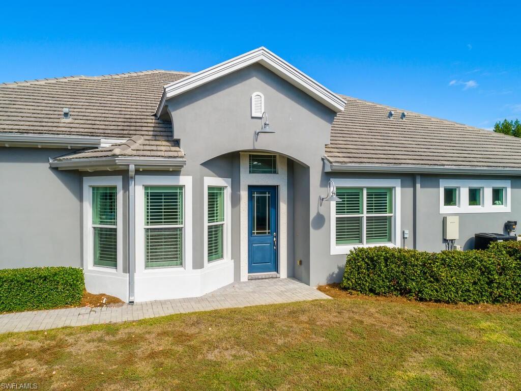 Entrance to property featuring a lawn, a tile roof, and stucco siding.