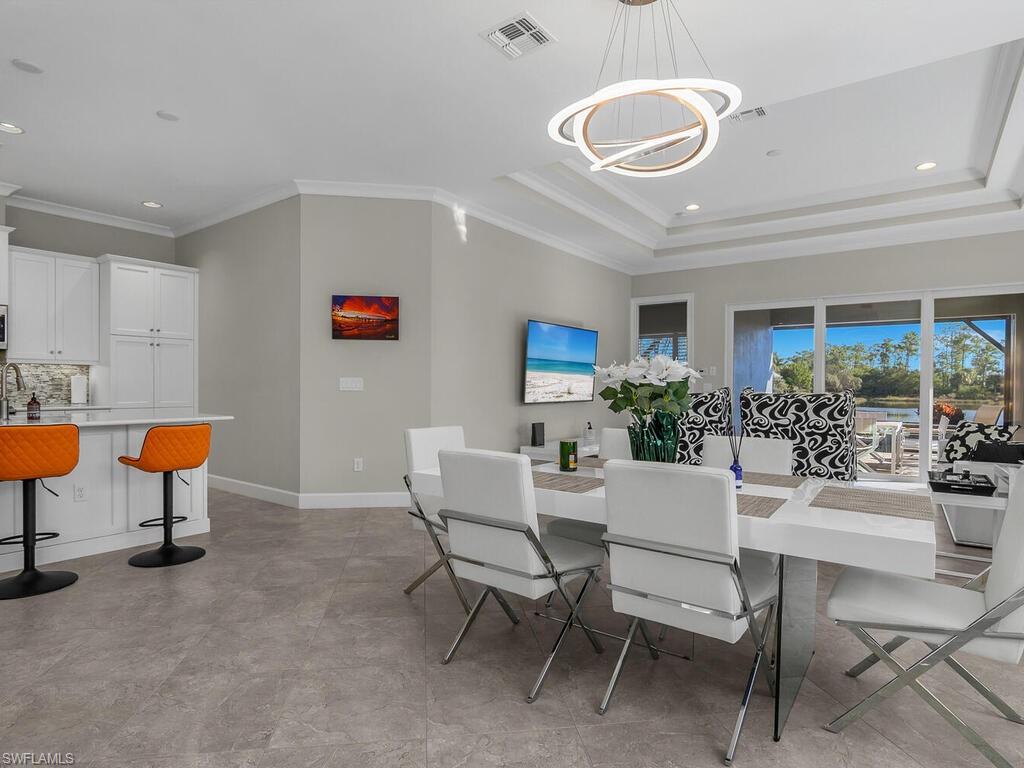 Dining area with recessed lighting, ornamental molding, a tray ceiling, and a chandelier.