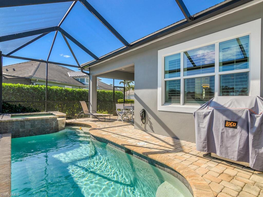 View of pool featuring area for grilling, a sunroom, a patio area, and glass enclosure