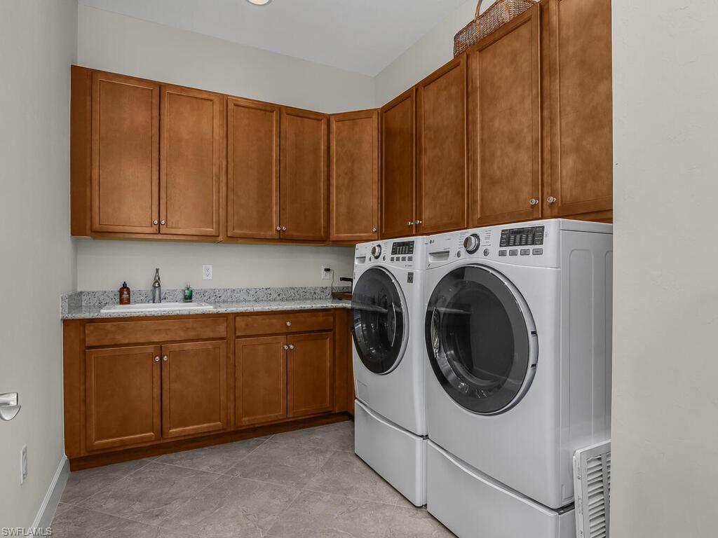 Large Laundry room with upgraded washer and dryer, light tile patterned floors, and lots of cabinet space, laundry sink.