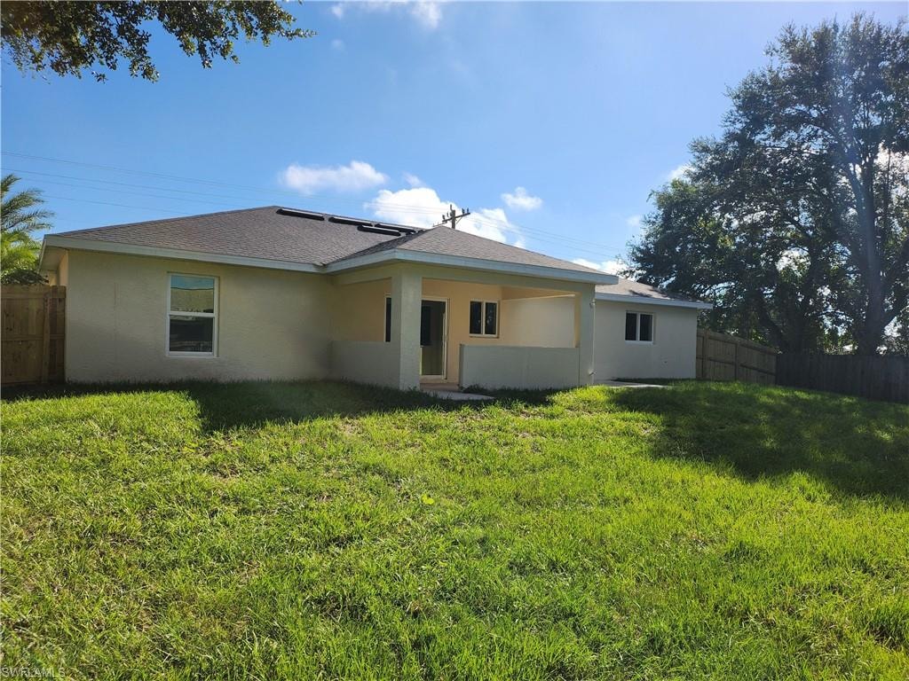 Back of house with stucco siding and roof with shingles