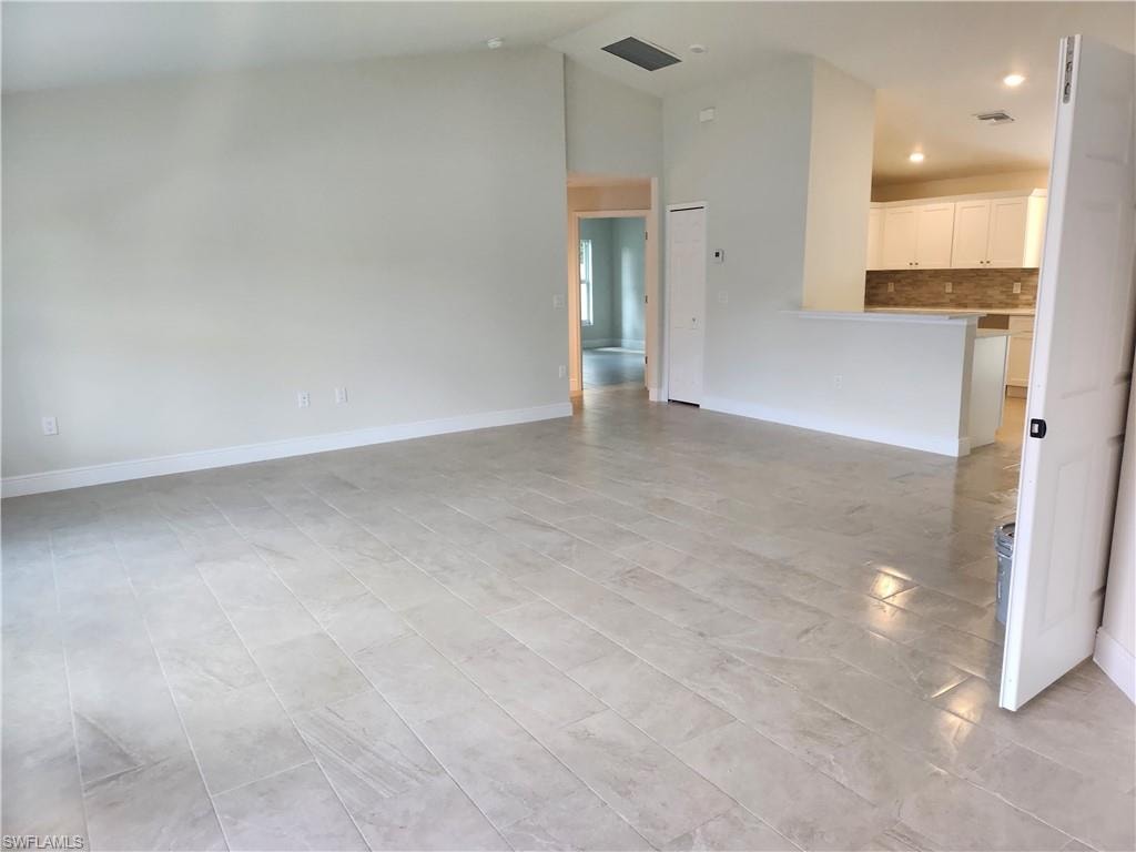 Unfurnished living room featuring baseboards and recessed lighting