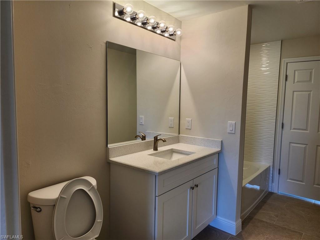 Bathroom with vanity, a bath, and dark tile patterned floors