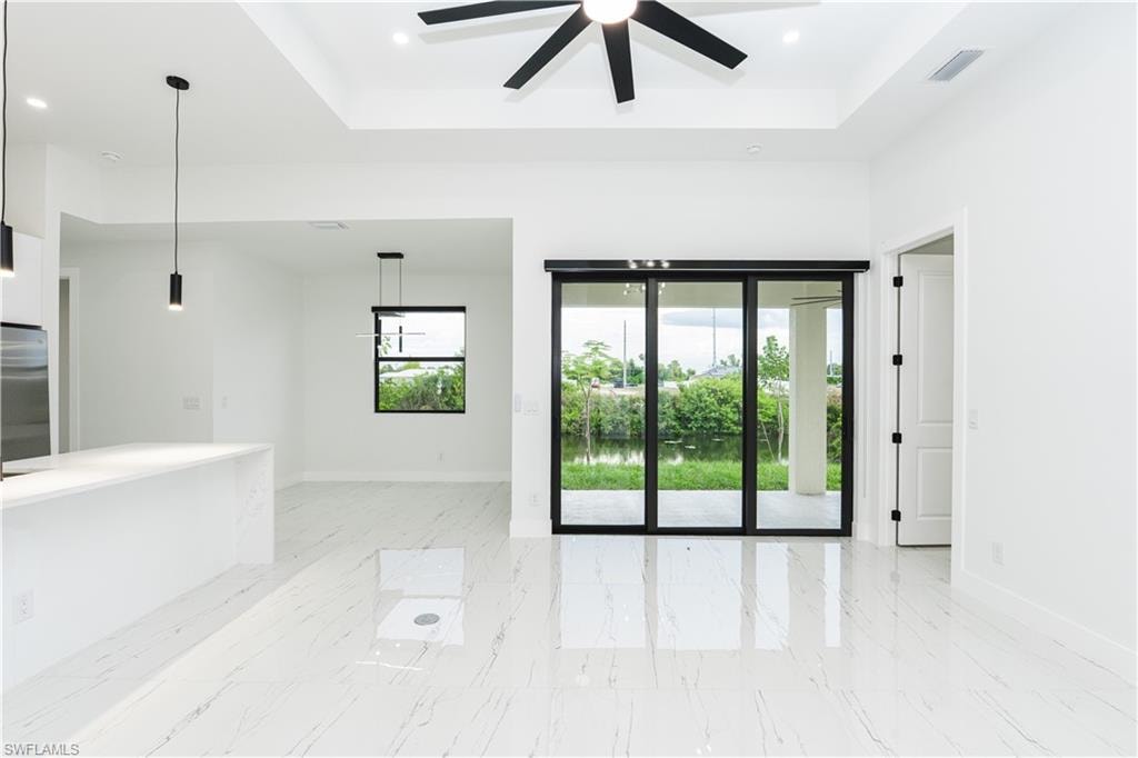 Kitchen featuring white cabinetry, hanging light fixtures, modern cabinets, a center island with sink, and light stone counters