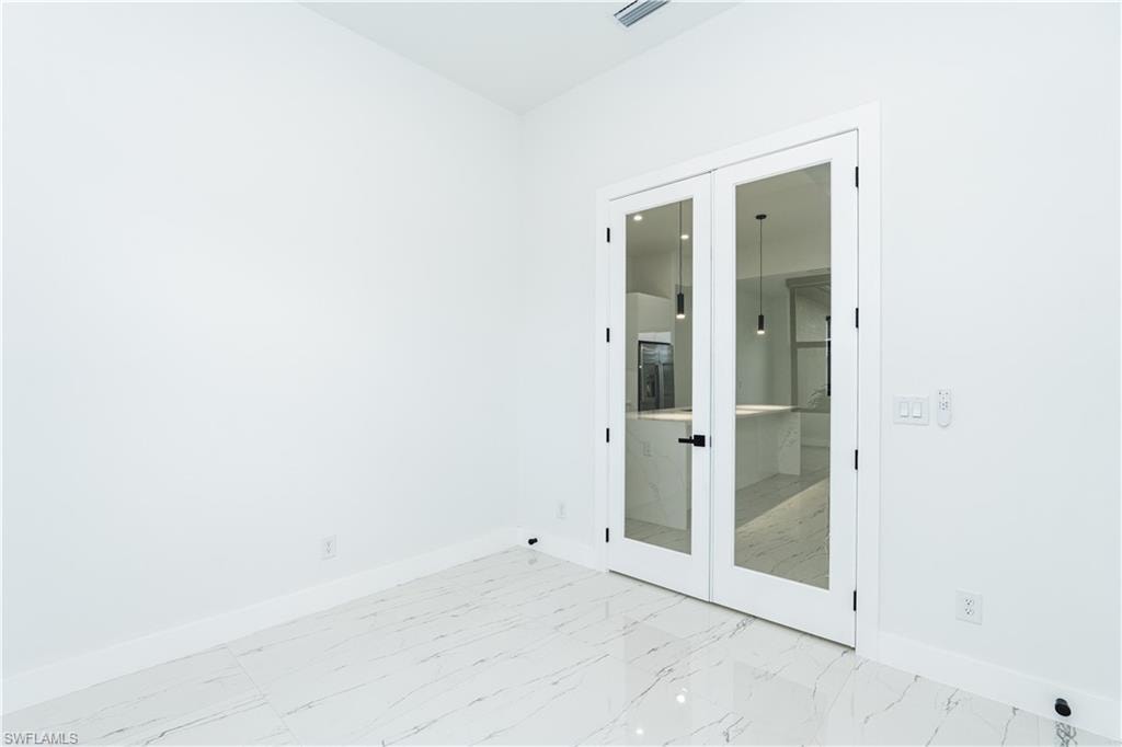 Spare room featuring french doors and light marble finish floors
