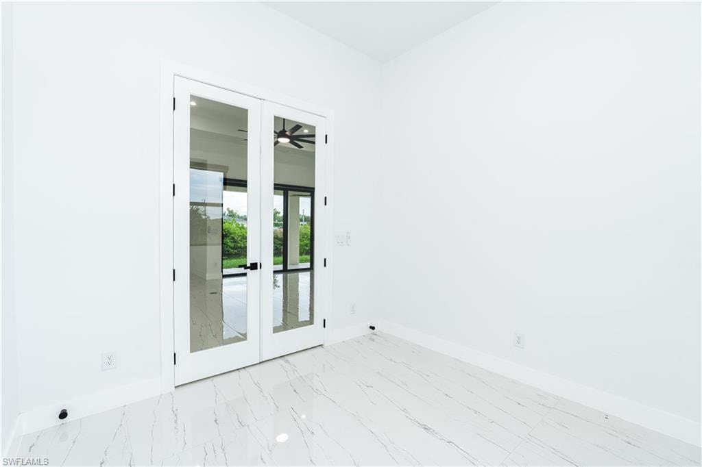 Empty room with ceiling fan, a tray ceiling, light marble finish floors, a towering ceiling, and a chandelier