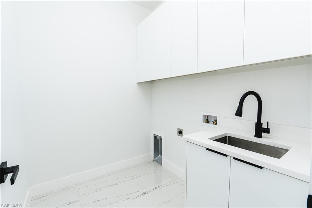 Kitchen featuring backsplash, appliances with stainless steel finishes, pendant lighting, an island with sink, and white cabinets