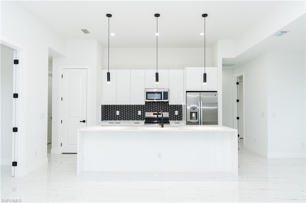 Unfurnished living room with a raised ceiling, light marble finish flooring, recessed lighting, ceiling fan, and a water view
