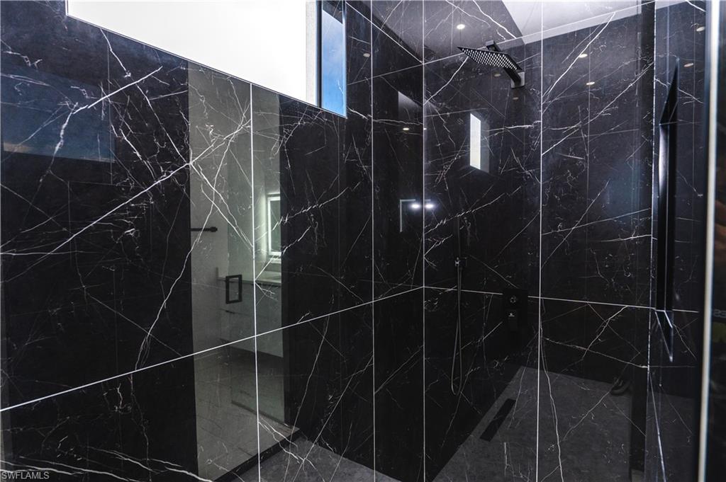 Bathroom view of vanity and a marble finish shower