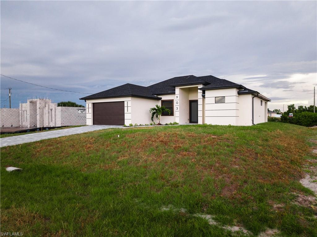 Prairie-style house featuring driveway, stucco siding, a front lawn, and a garage