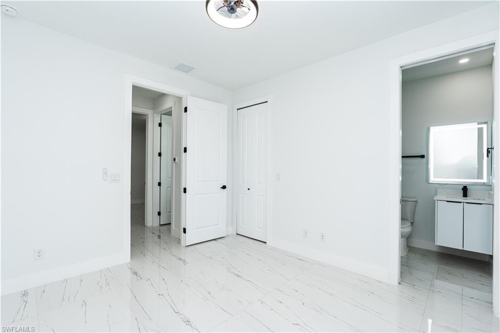 Unfurnished bedroom featuring light marble finish floors and a closet