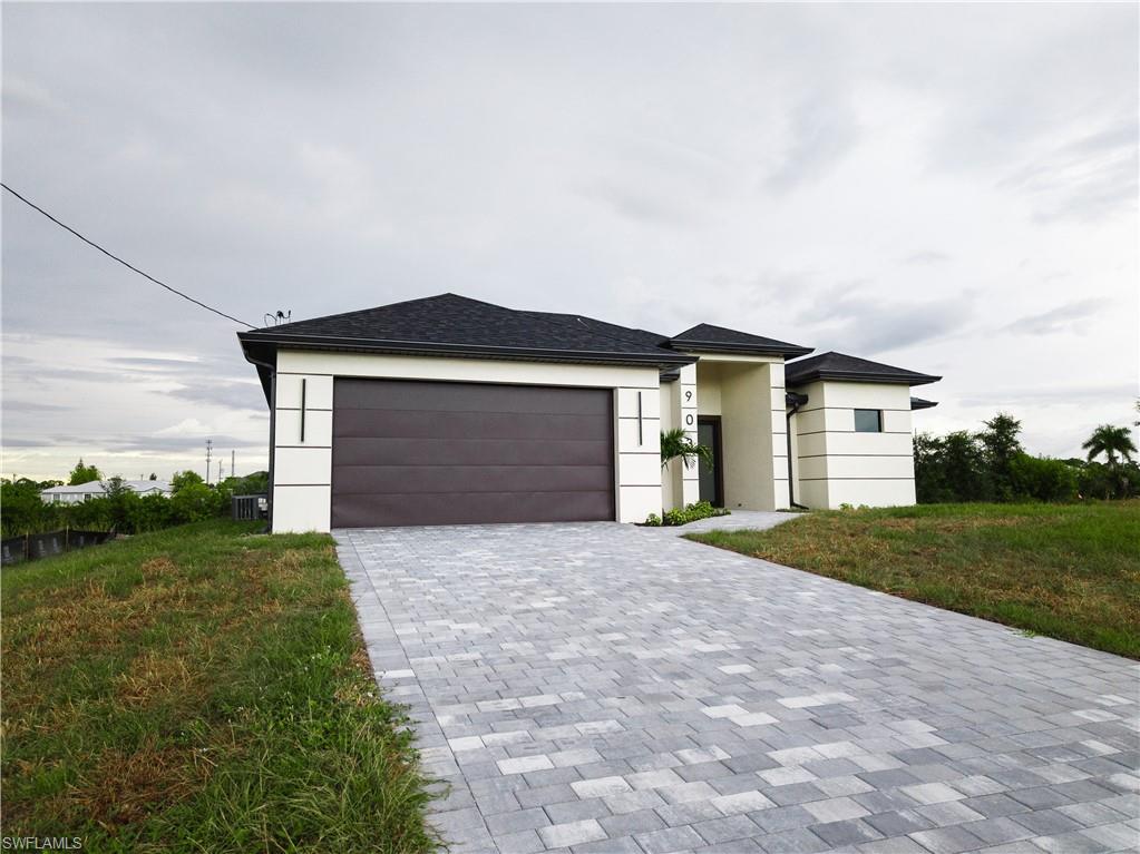 View of front of house featuring decorative driveway, stucco siding, an attached garage, and a front lawn