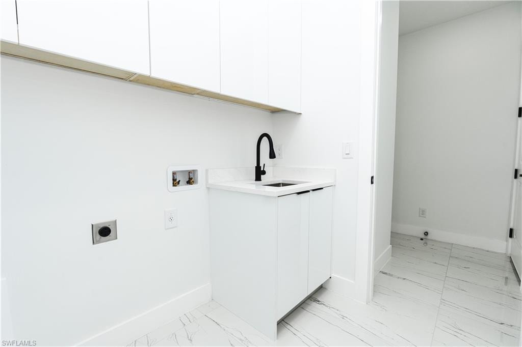 Washroom featuring cabinet space, hookup for an electric dryer, light marble finish flooring, and washer hookup