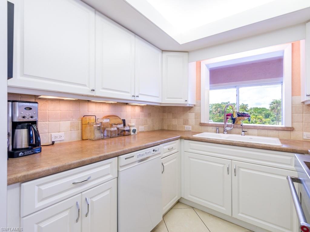 Kitchen with white cabinets, white appliances, decorative backsplash, light tile patterned floors, and light countertops
