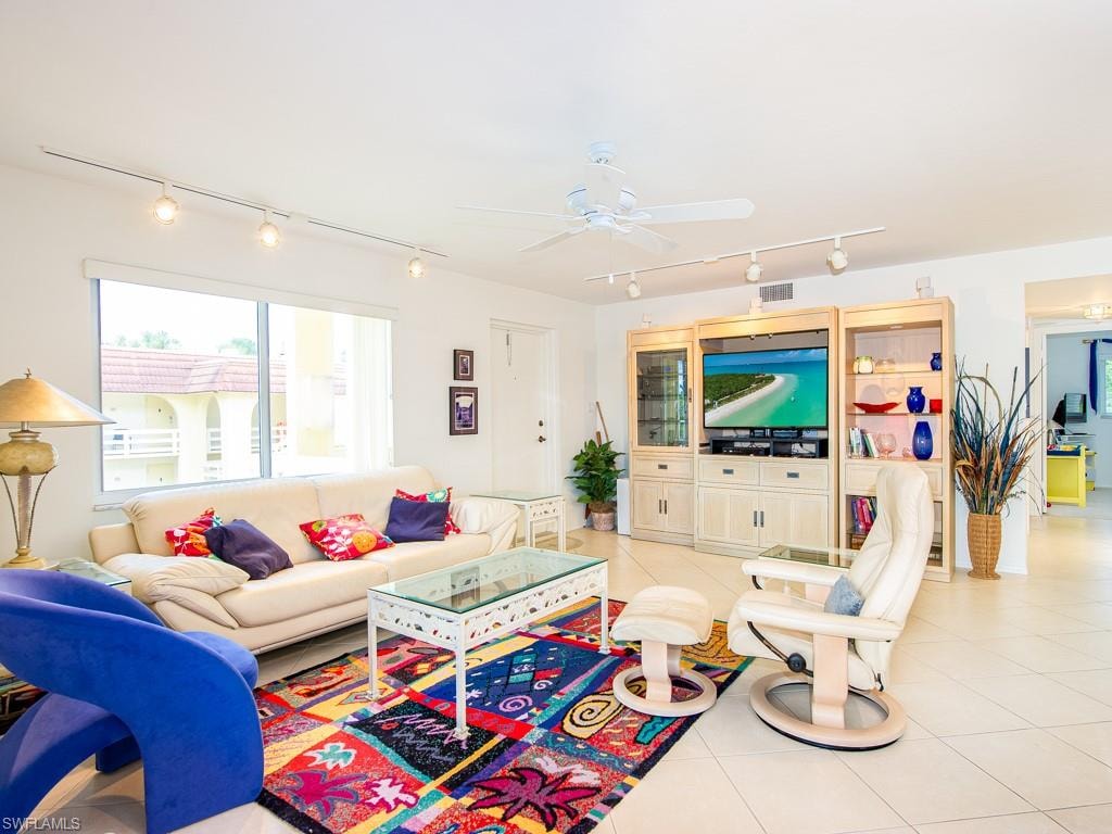 Living area featuring rail lighting, light tile patterned flooring, and ceiling fan