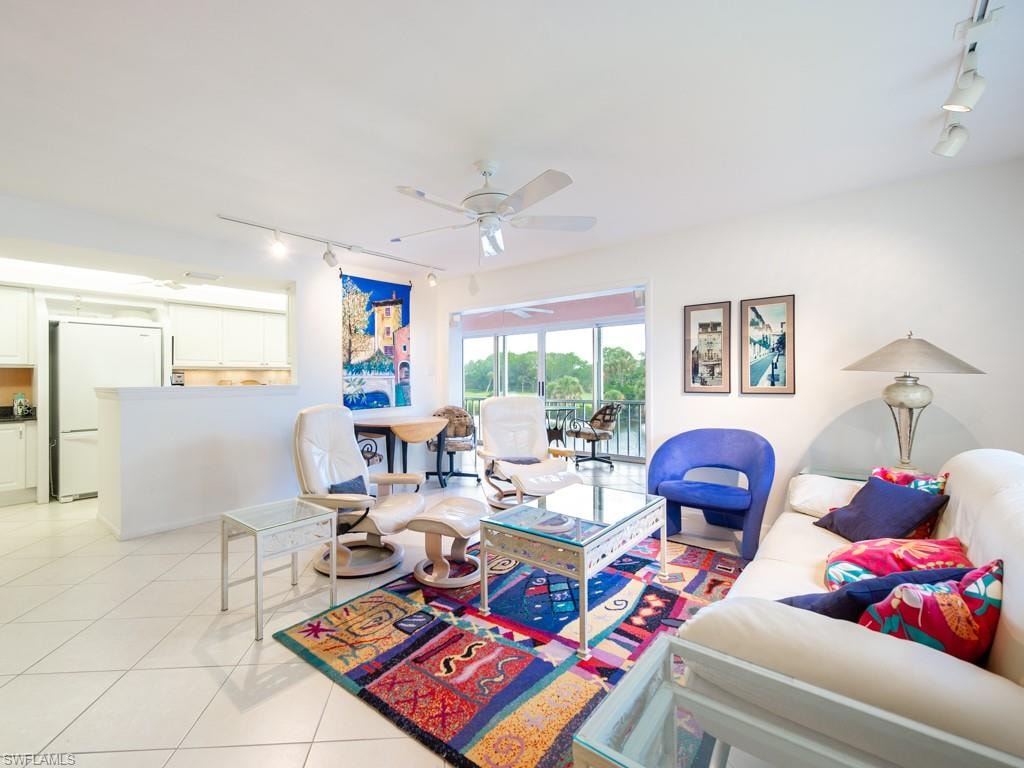 Living room with rail lighting, light tile patterned floors, and a ceiling fan