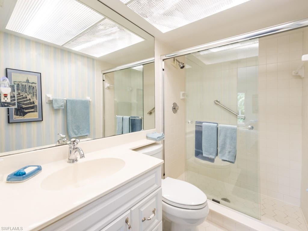 Full bathroom with vanity, wallpapered walls, and a stall shower