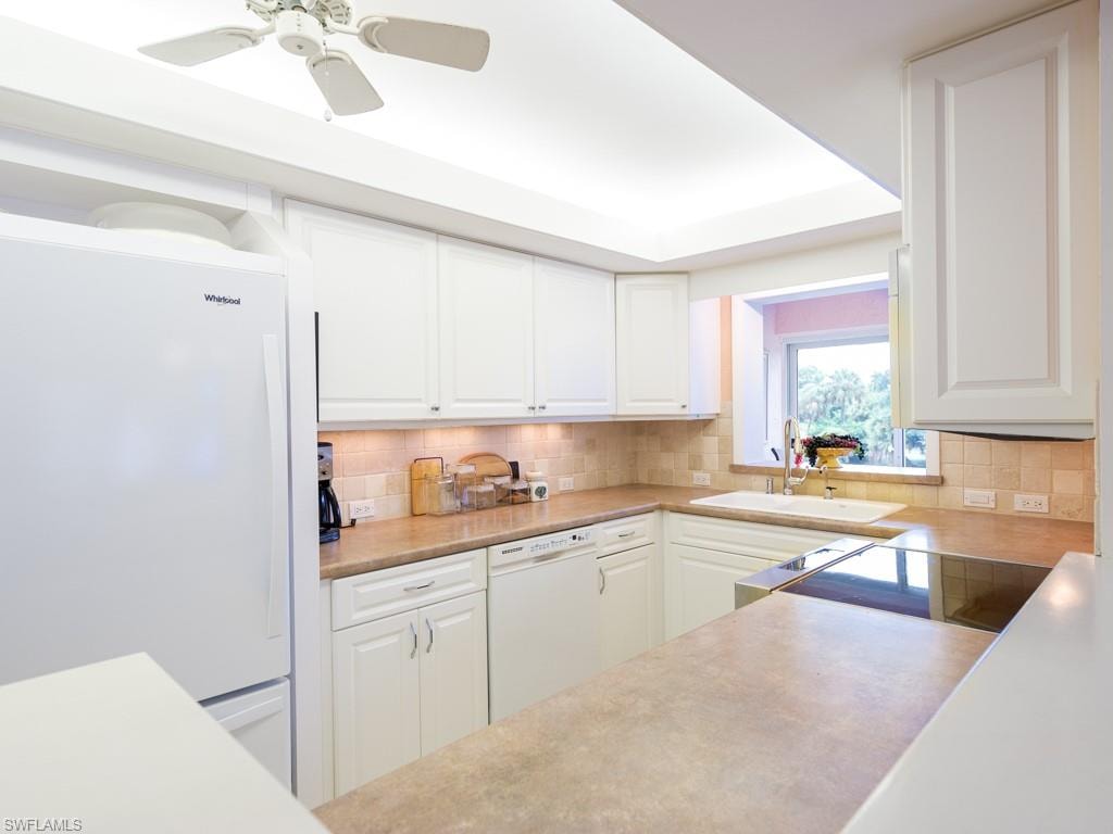 Kitchen with white appliances, light countertops, and white cabinetry